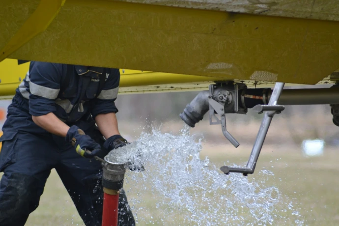 person in black and yellow wet suit holding black and yellow water hose